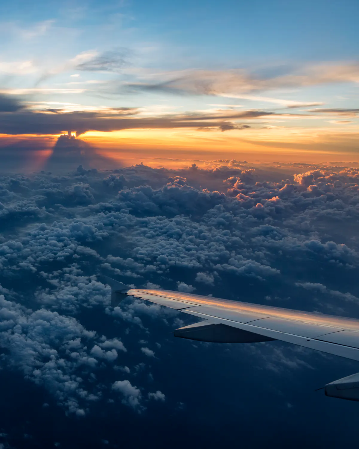 Aircraft wing over clouds at sunset
